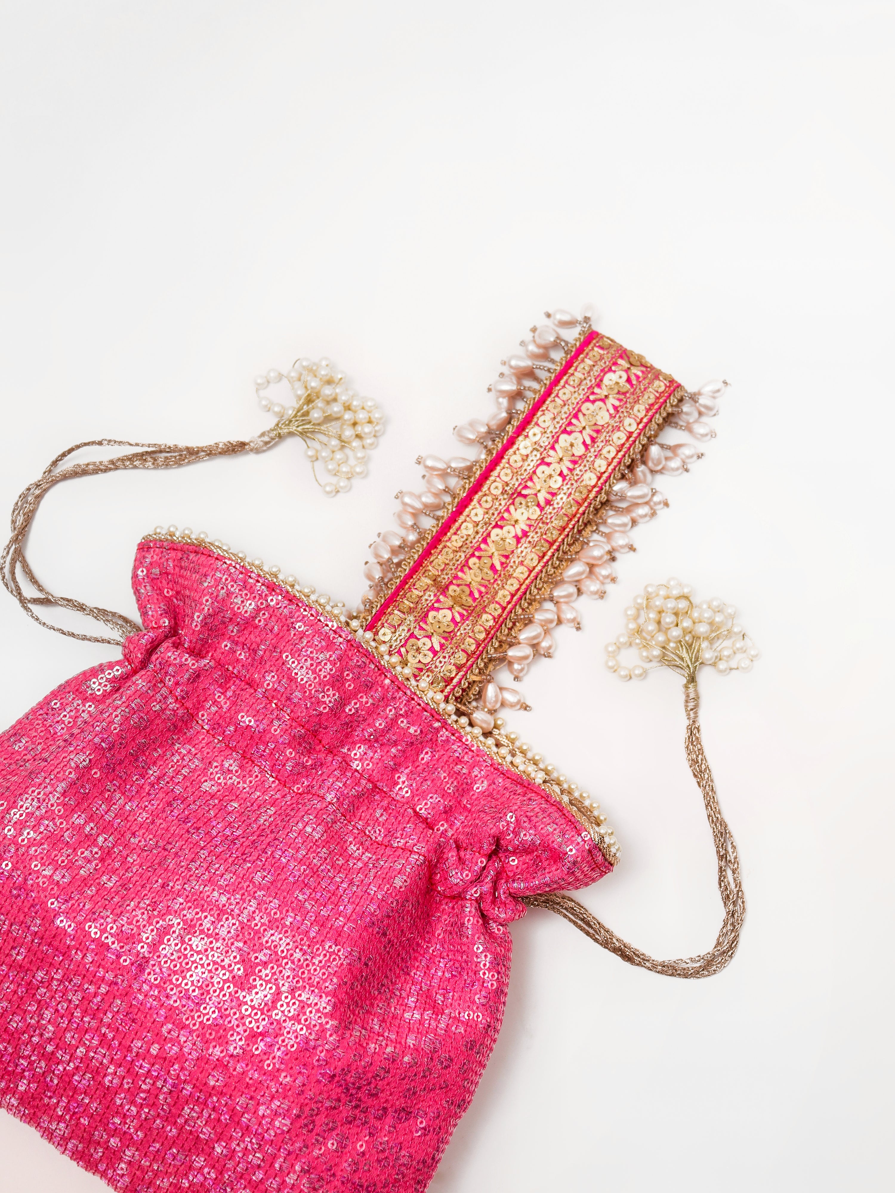 Pink drawstring bag with decorative elements on a white background. With pearl handle
