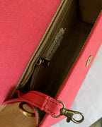 Rust sling bag with a zipper and a doghook clasp for keys on a wooden surface